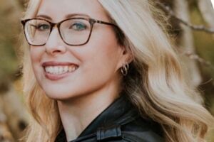 Close-up portrait of Megan smiling, wearing black shirt and a blurred background