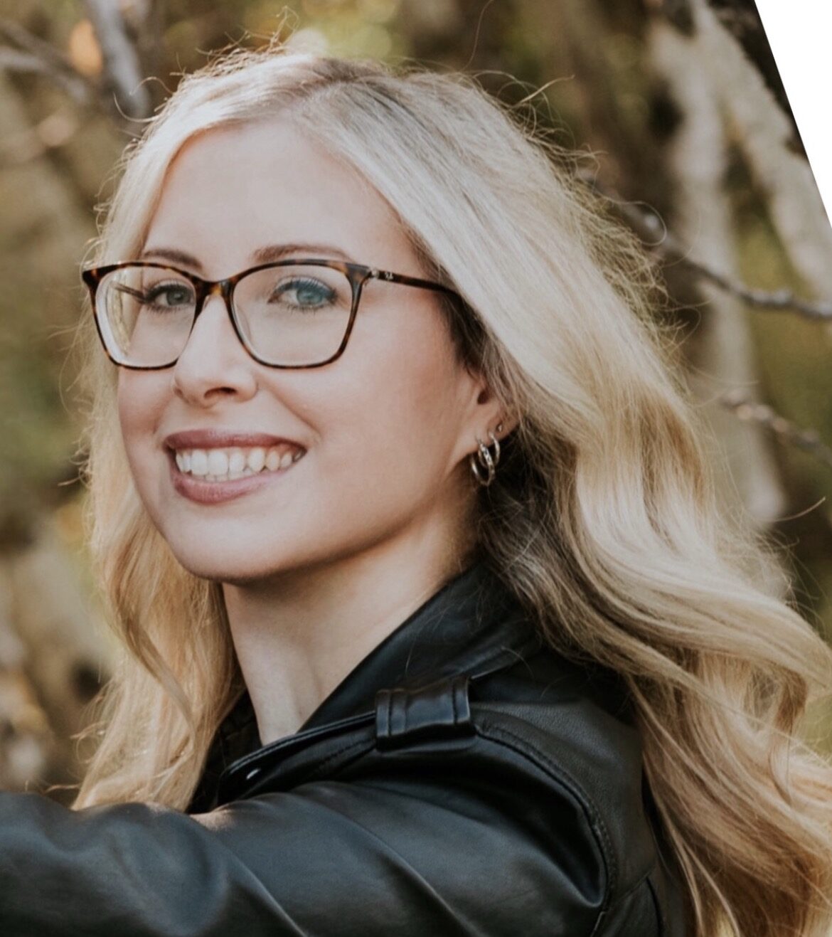 Close-up portrait of Megan smiling, wearing black shirt and a blurred background