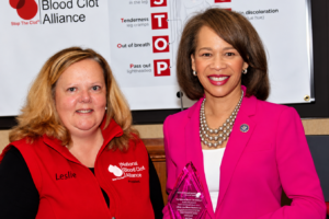 Leslie Lake, Volunteer President of the National Blood Clot Alliance, standing with U.S. Senator Lisa Blunt Rochester as she holds NBCA's Blood Clot Advocate Award.
