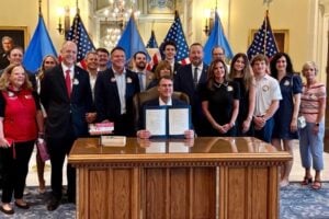 group of advocates gathered around Governor Kevin Stitt's desk for bill signing
